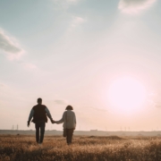 couple holding hands while walking on grass field during daytime